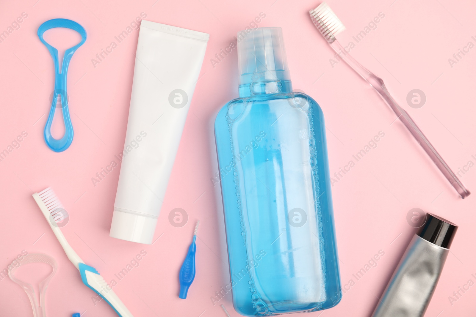 Photo of Mouthwash and other oral hygiene products on pink background, flat lay