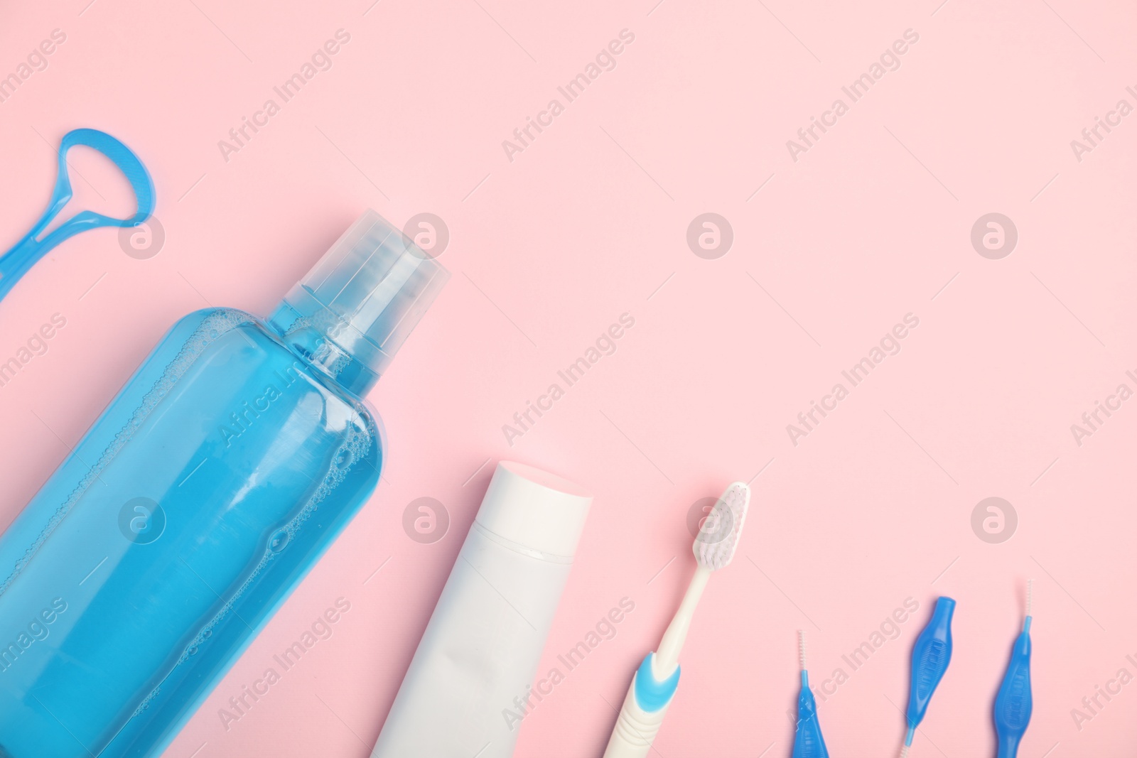 Photo of Mouthwash and other oral hygiene products on pink background, flat lay. Space for text