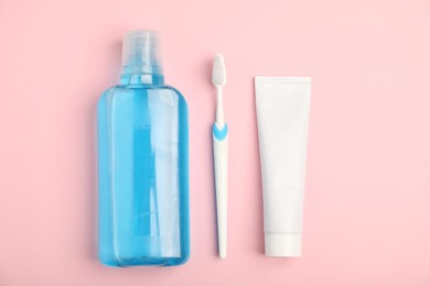 Photo of Mouthwash, toothbrush and toothpaste on pink background, flat lay