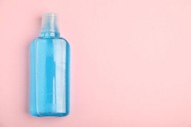 Photo of Bottle of mouthwash on pink background, top view. Space for text