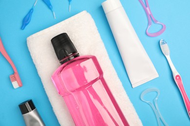 Photo of Mouthwash and other oral hygiene products on light blue background, flat lay