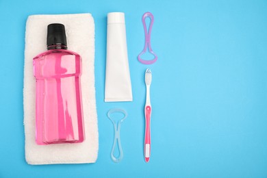 Photo of Mouthwash and other oral hygiene products on light blue background, flat lay. Space for text