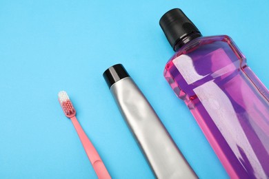 Photo of Mouthwash, toothbrush and toothpaste on light blue background, closeup