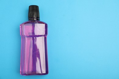 Photo of Bottle of mouthwash on light blue background, top view. Space for text