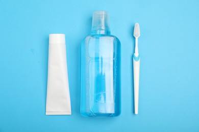 Photo of Mouthwash, toothbrush and toothpaste on light blue background, flat lay