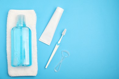 Photo of Mouthwash and other oral hygiene products on light blue background, flat lay. Space for text
