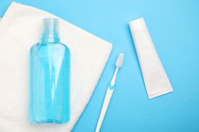 Photo of Mouthwash and other oral hygiene products on light blue background, flat lay