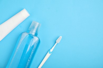 Photo of Mouthwash, toothbrush and toothpaste on light blue background, flat lay. Space for text