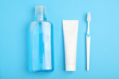 Photo of Mouthwash, toothbrush and toothpaste on light blue background, flat lay