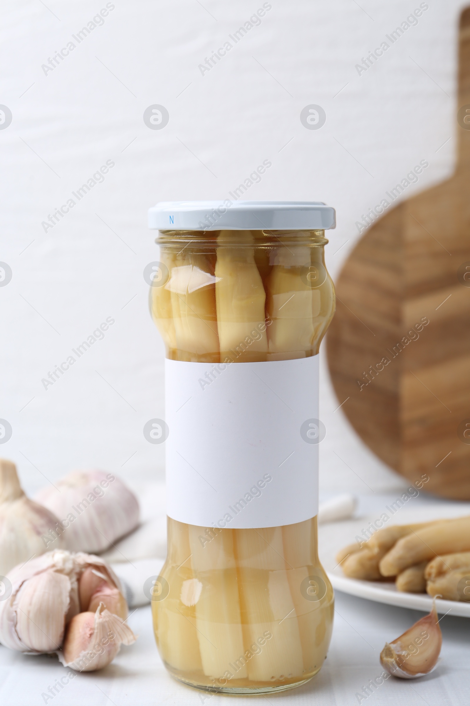 Photo of Pickled asparagus and garlic on white tiled table