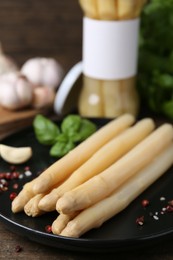 Photo of Pickled asparagus and spices on wooden table, closeup