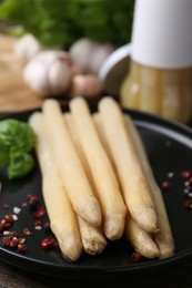 Photo of Pickled asparagus and spices on wooden table, closeup