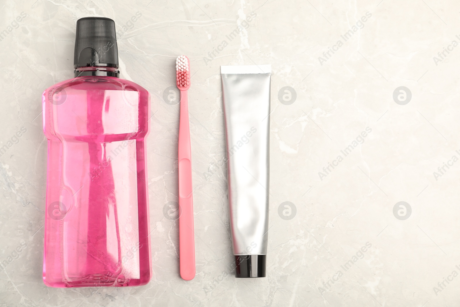 Photo of Mouthwash, toothbrush and toothpaste on light marble table, flat lay. Space for text