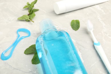 Photo of Mouthwash, other oral hygiene products and mint on light marble table, closeup