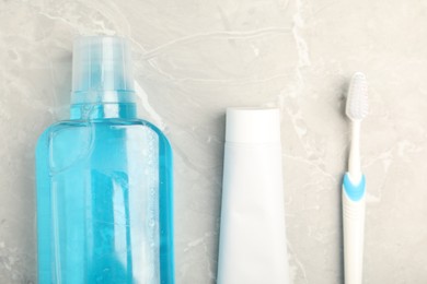Photo of Mouthwash, toothbrush and toothpaste on light marble table, flat lay