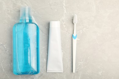 Photo of Mouthwash, toothbrush and toothpaste on light marble table, flat lay