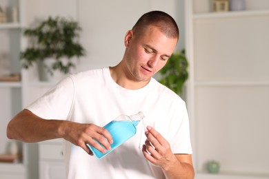 Photo of Man with bottle of mouthwash at home