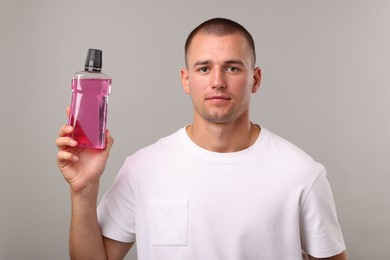 Photo of Man with bottle of mouthwash on light grey background