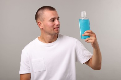 Photo of Man with bottle of mouthwash on light grey background