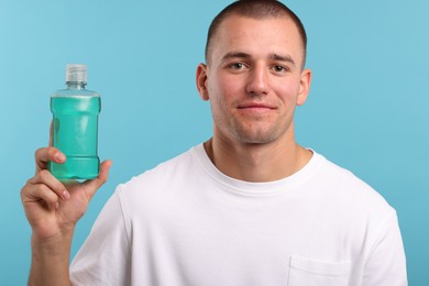 Photo of Man with bottle of mouthwash on blue background