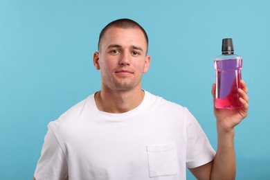 Photo of Man with bottle of mouthwash on blue background