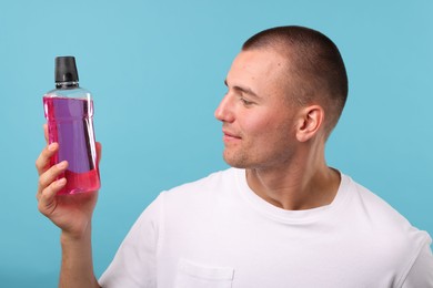 Photo of Man with bottle of mouthwash on blue background