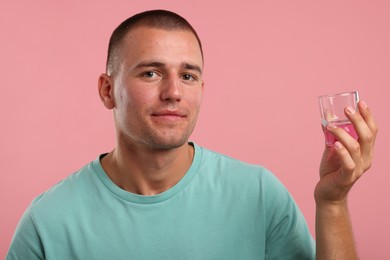 Photo of Man with glass of mouthwash on pink background