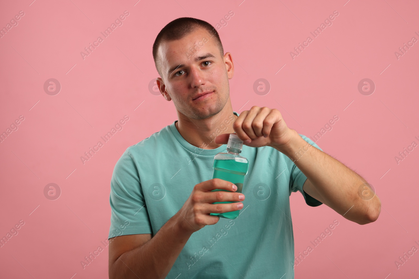 Photo of Man with bottle of mouthwash on pink background
