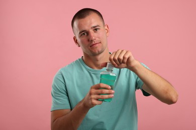 Photo of Man with bottle of mouthwash on pink background