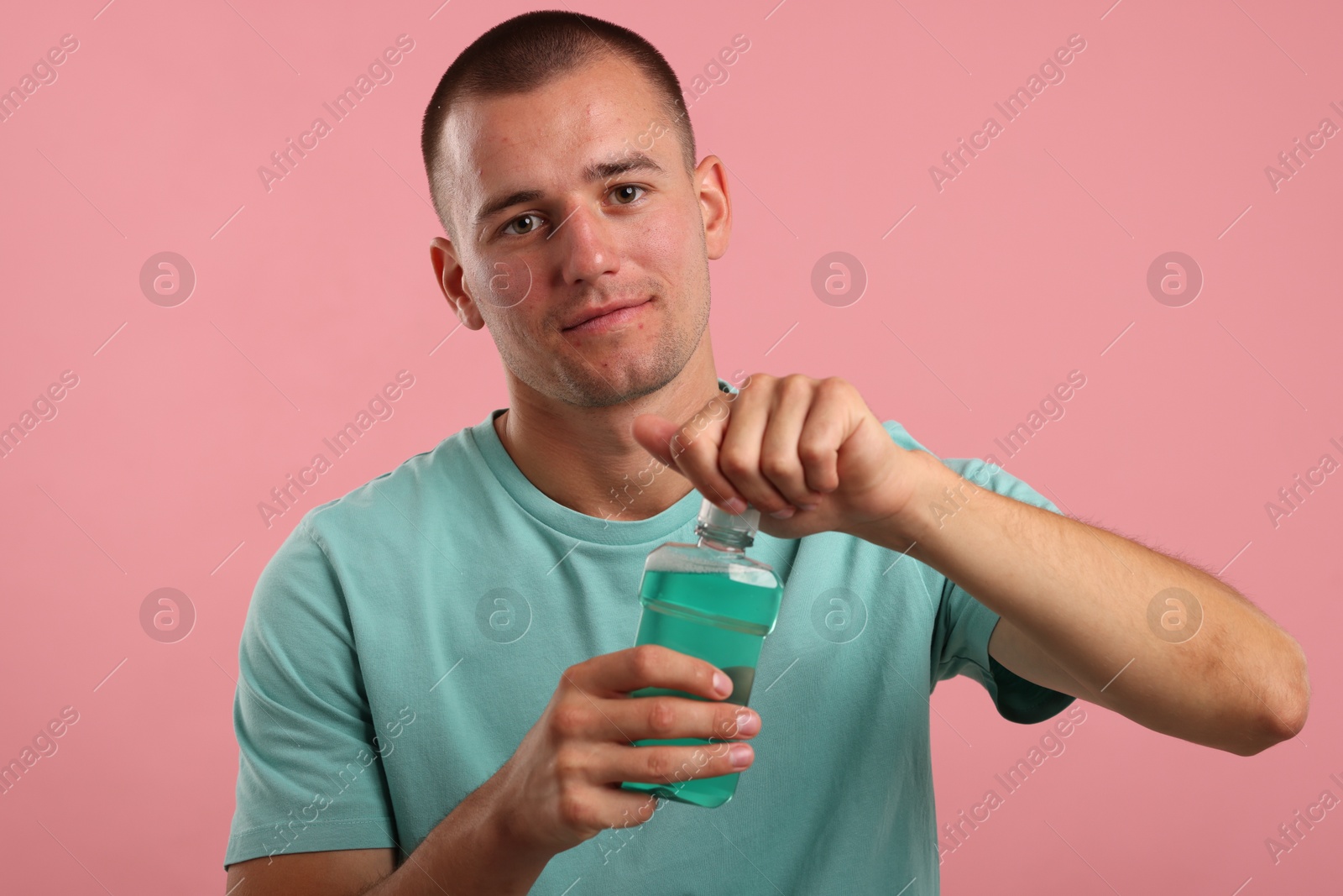Photo of Man with bottle of mouthwash on pink background