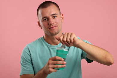 Photo of Man with bottle of mouthwash on pink background