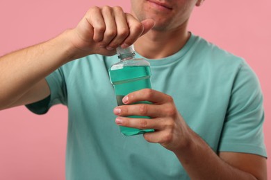 Photo of Man with bottle of mouthwash on pink background, closeup