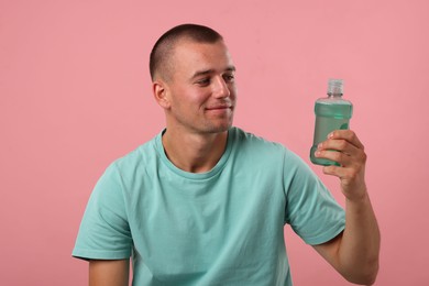 Photo of Man with bottle of mouthwash on pink background