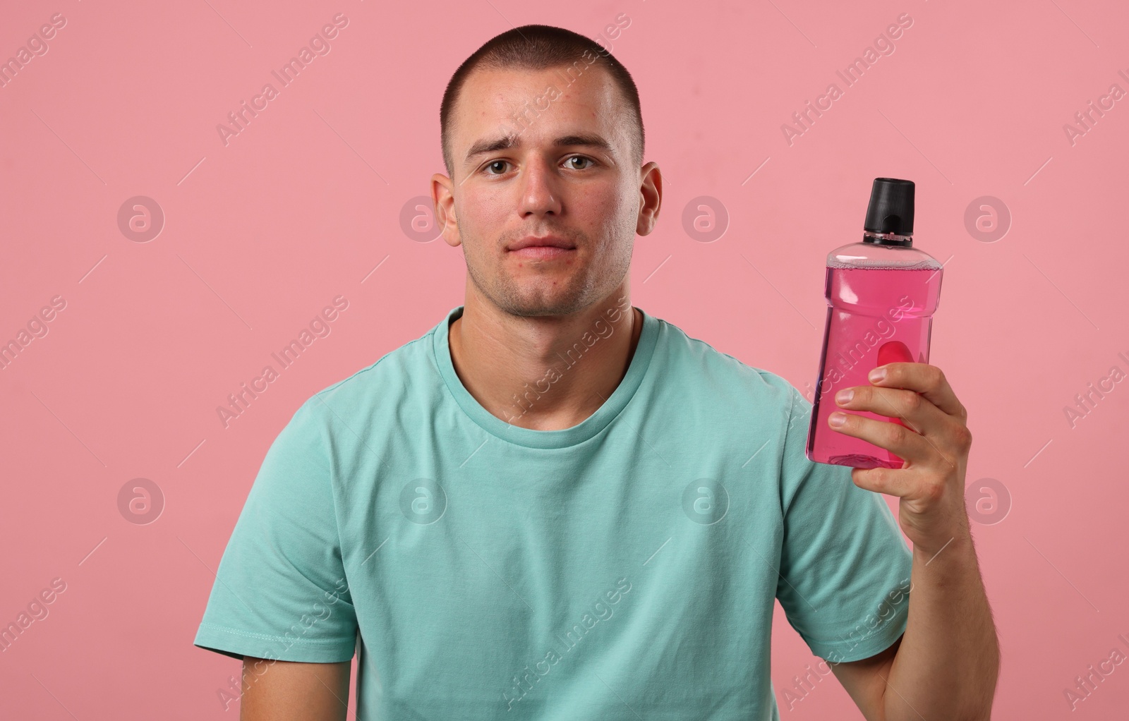 Photo of Man with bottle of mouthwash on pink background