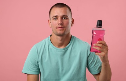 Photo of Man with bottle of mouthwash on pink background