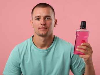 Photo of Man with bottle of mouthwash on pink background