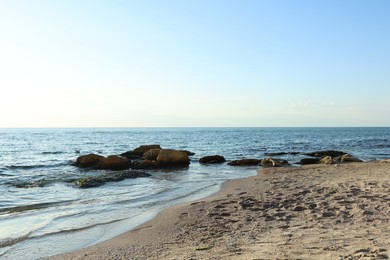 Photo of Beautiful wavy sea, stones and sandy beach