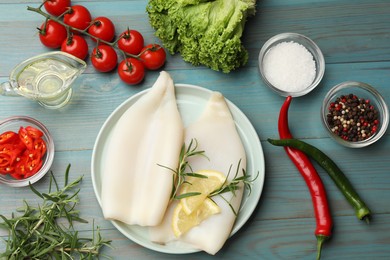 Photo of Uncooked squids with lemon slices, rosemary and spices on blue wooden table, flat lay