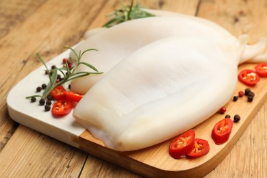 Photo of Uncooked squids with spices on wooden table, closeup