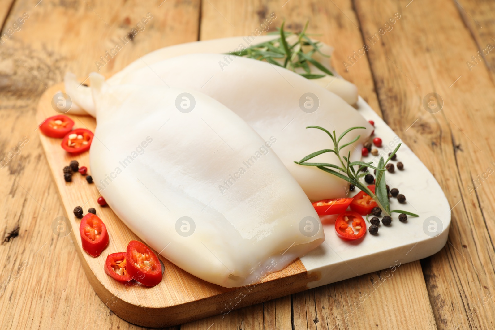 Uncooked squids with spices on wooden table, closeup Photo of Uncooked squids with spices on wooden table, closeup