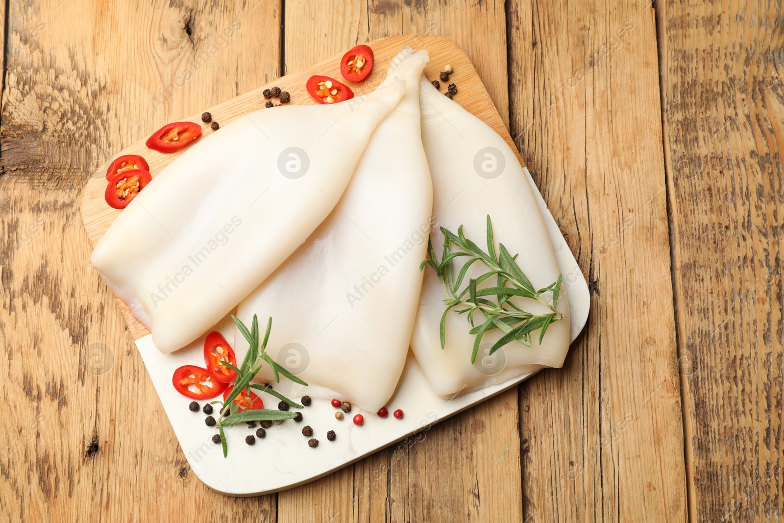 Uncooked squids with spices on wooden table, top view Photo of Uncooked squids with spices on wooden table, top view