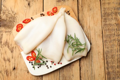 Photo of Uncooked squids with spices on wooden table, top view