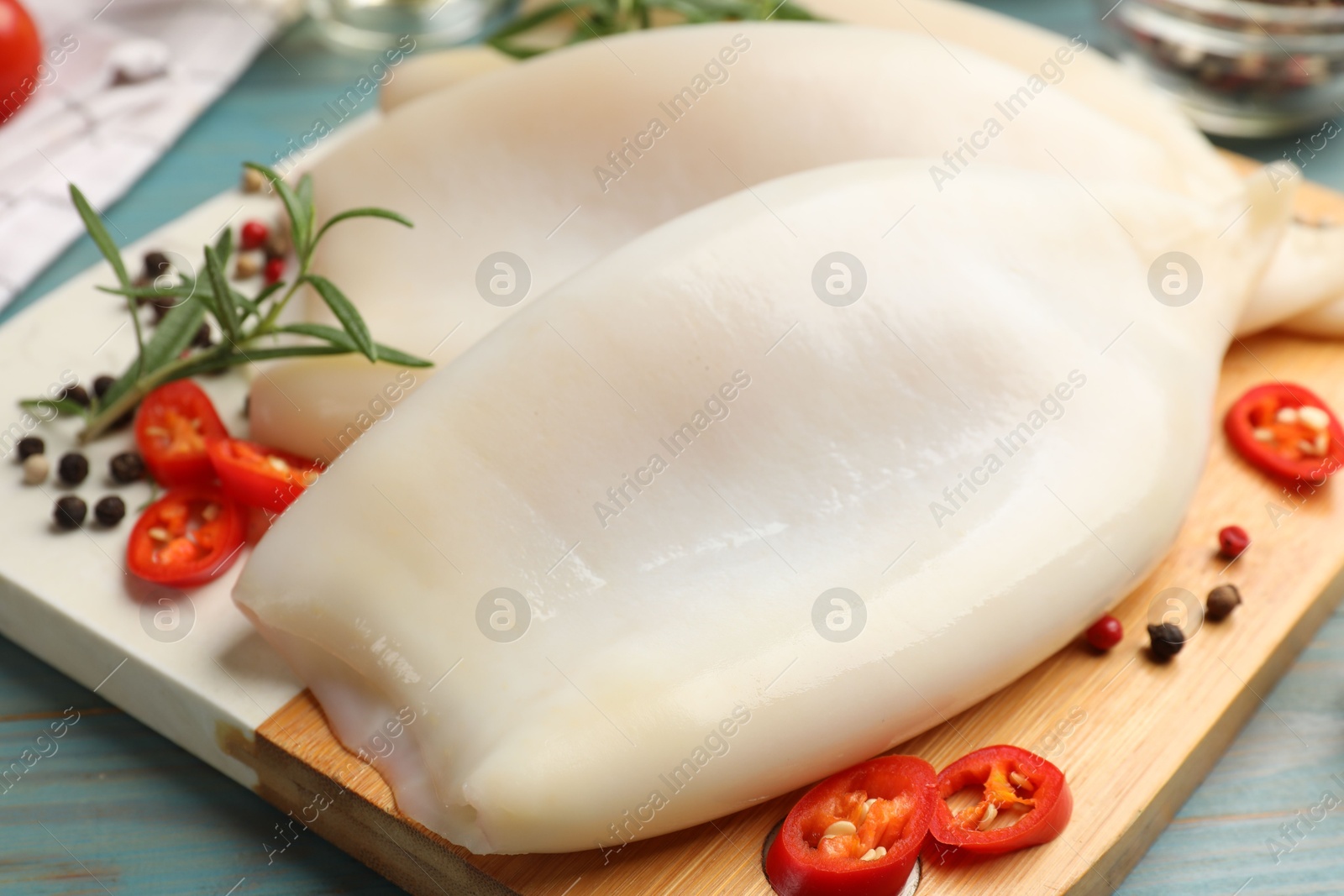 Photo of Uncooked squids with spices on blue wooden table, closeup