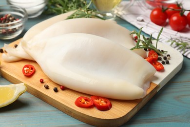 Photo of Uncooked squids with spices on blue wooden table, closeup