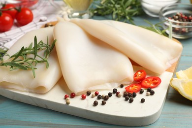 Photo of Uncooked squids with spices on blue wooden table, closeup