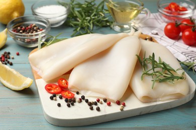 Photo of Uncooked squids with spices on blue wooden table, closeup