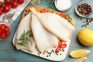 Photo of Uncooked squids with spices on blue wooden table, flat lay