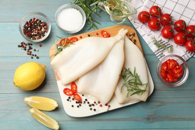 Photo of Uncooked squids with spices on blue wooden table, flat lay