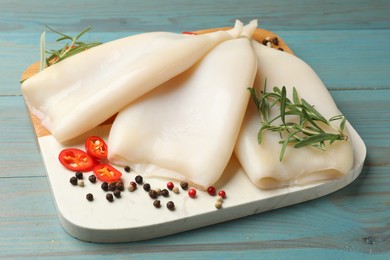 Photo of Uncooked squids with spices on blue wooden table, closeup