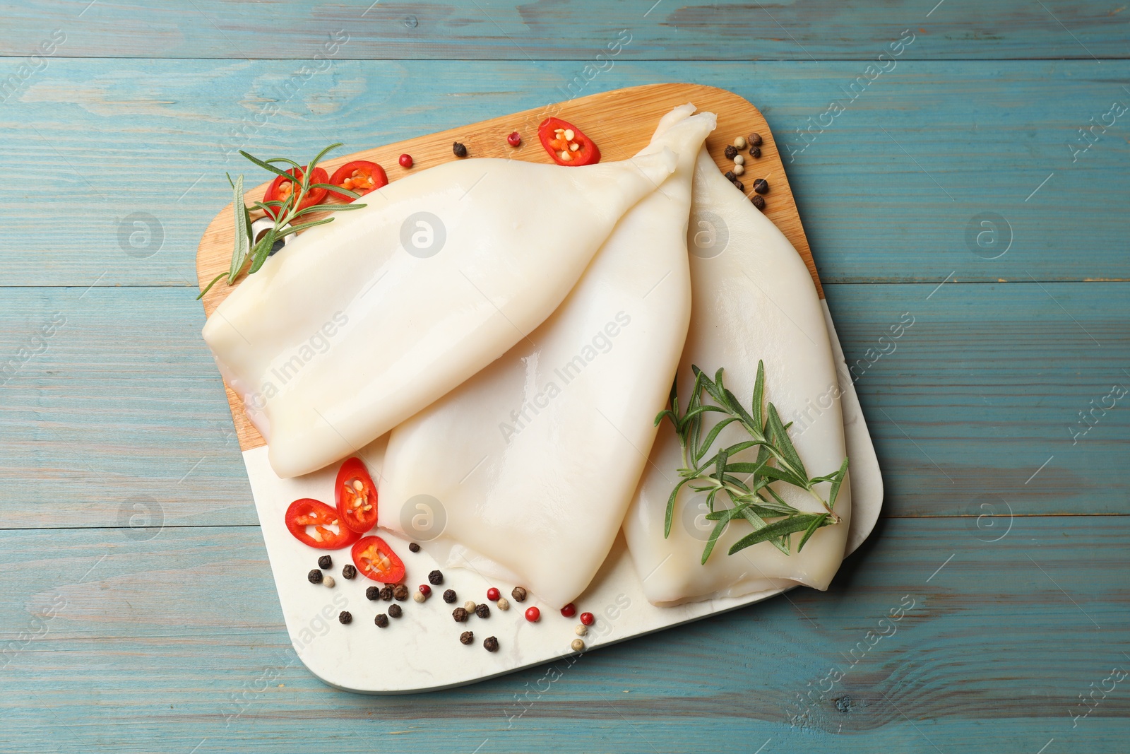 Photo of Uncooked squids with spices on blue wooden table, top view